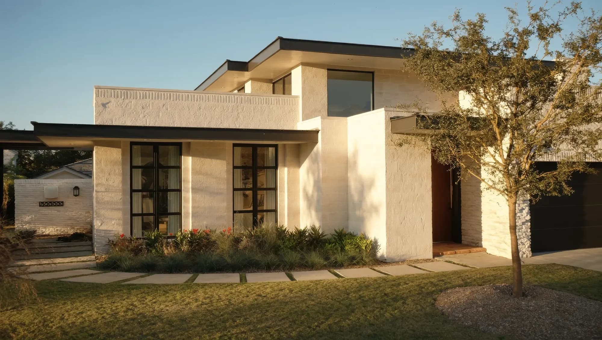 A modern limestone family home in late-afternoon light